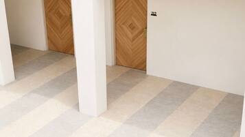 A multi-level interior with a checkered floor pattern, a wooden door with a herringbone design, and a number '112' on the wall.
