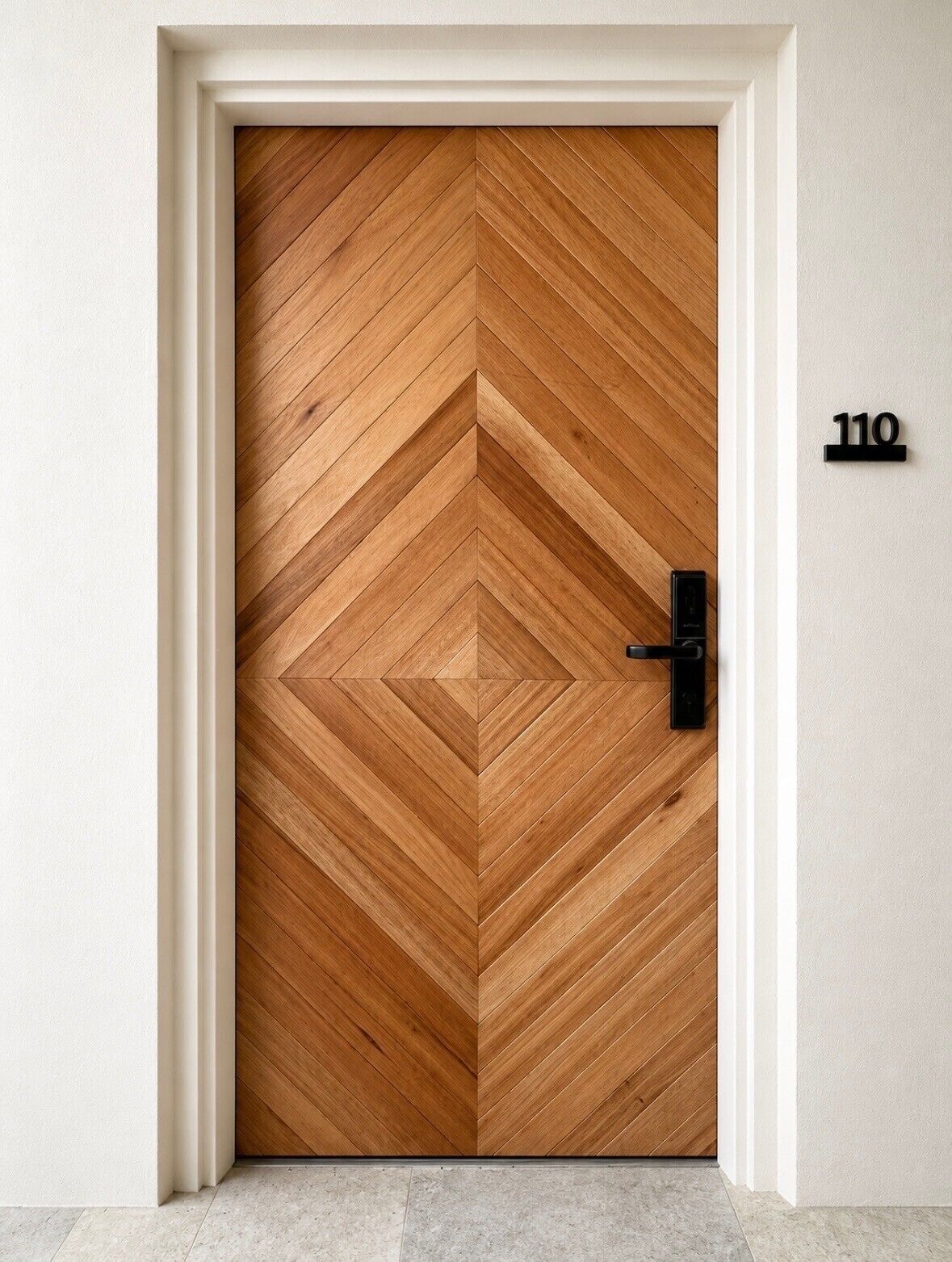 A wooden door with a chevron pattern, a black door handle, and a number '110' on the wall.