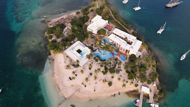 Vista aérea de una propiedad costera con playa, piscina y varios barcos.