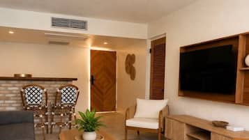 A modern living room with a ceiling fan, a TV mounted on the wall, a sofa, a coffee table, and a dining area with chairs.