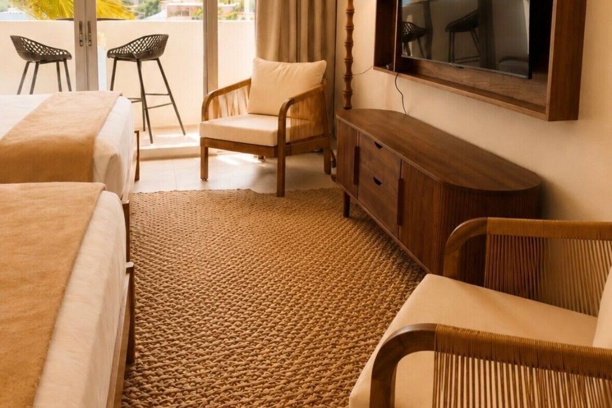 A hotel room with two beds, a TV, a chair, a lamp, and a view of palm trees.