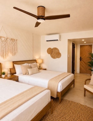 A hotel room with two beds, a ceiling fan, an air conditioning unit, macrame wall decor, and a wooden door. - Hotel on the Cay (Christiansted)