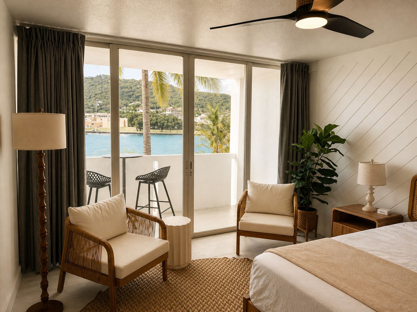 A hotel room with a bed, two chairs, a small table, a lamp, a potted plant, and a view of a body of water and hills.