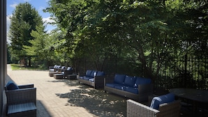 An outdoor seating area with wicker furniture and a paved patio. - SpringHill by Marriott Centreville/Chantilly (Centreville)