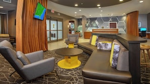 A hotel lobby with a reception desk, seating area, and a television mounted on the wall. - SpringHill by Marriott Centreville/Chantilly (Centreville)