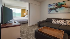 A hotel room with a bed, a sofa, a TV, a coffee table, and a painting on the wall. - SpringHill by Marriott Centreville/Chantilly (Centreville)