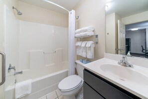 Een moderne badkamer met een bad, toilet en wastafel.
