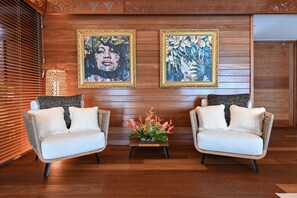 A room with two white sofas, a small table with a floral arrangement, and two framed artworks on the wall.