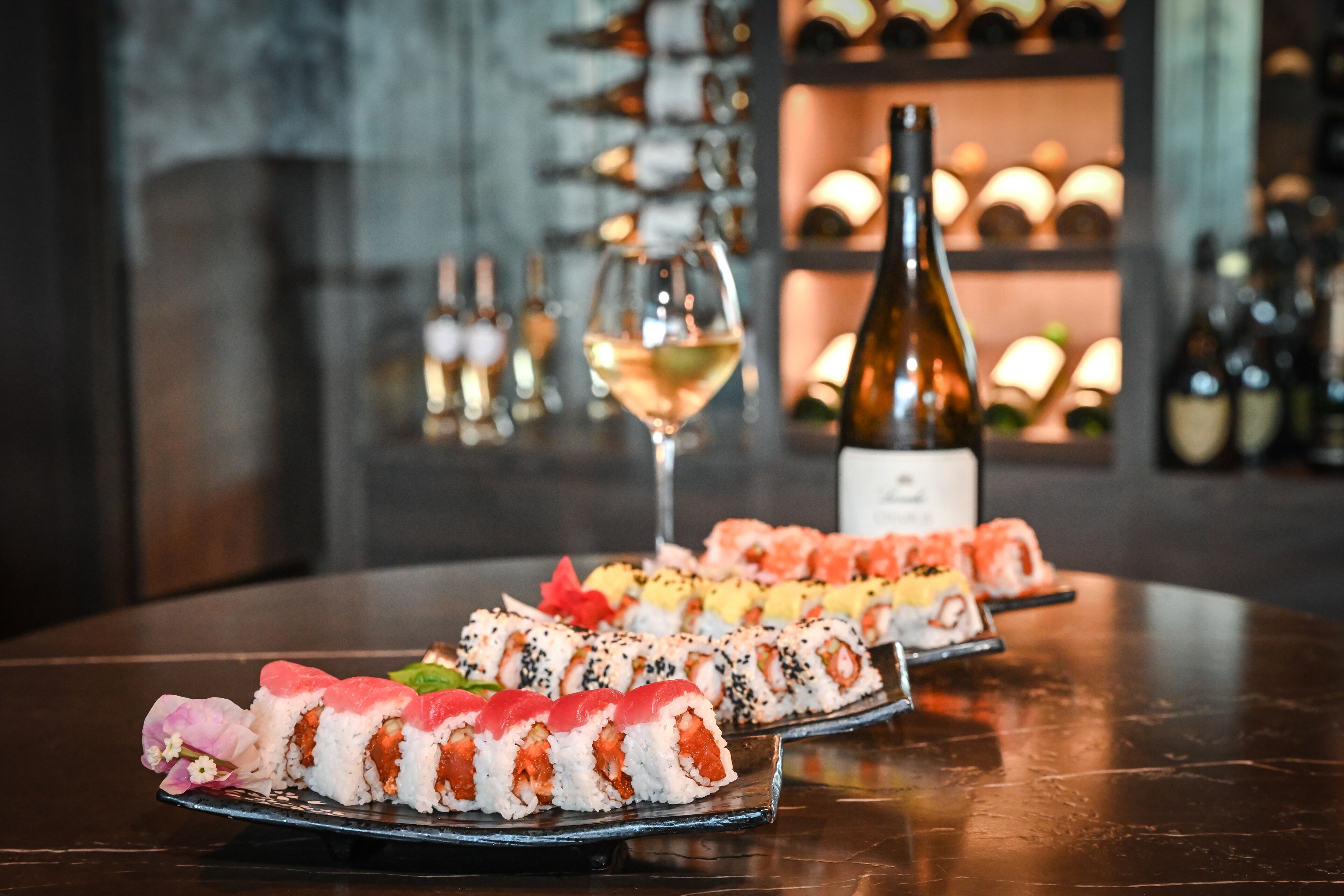 Une table avec différents plats de sushis et une bouteille de vin.