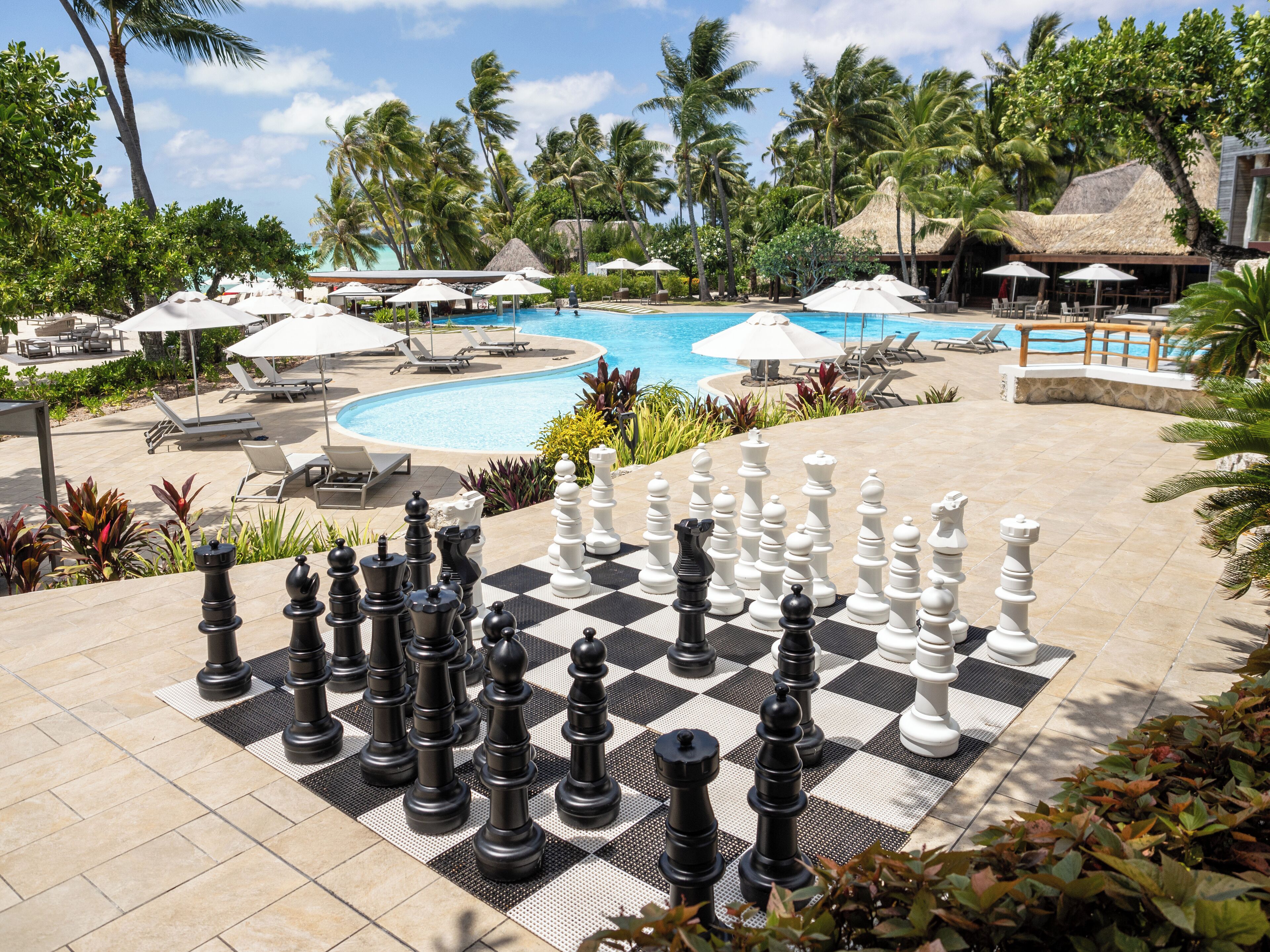 A poolside chessboard with a tropical resort backdrop.