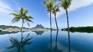 Una playa con palmeras y una montaña al fondo, con vista despejada.