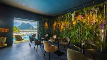 Un salón moderno con vistas a un paisaje tropical, que presenta una pared verde con plantas y un área de piscina.