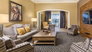 A hotel room with a sofa, armchairs, a coffee table, a TV, and a painting on the wall. - Club Wyndham Nashville (Nashville)