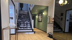 Una escalera con fotografías blanco y negro, una zona de recepción y un suelo de madera.