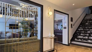 Zona de recepción con escalera, mostrador de recepción y área de descanso con separador de vidrio.