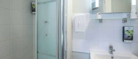 Un baño moderno con cabina de ducha de vidrio, un lavabo blanco y un espejo sobre él.