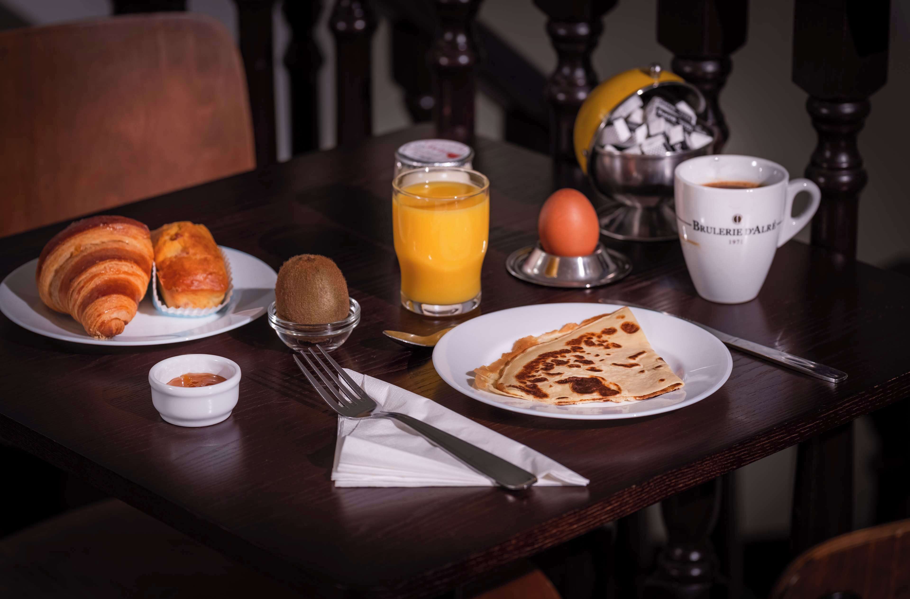 Un desayuno con croissants, un vaso de jugo de naranja, una taza de café, un plato con una rebanada de tostada y un tazón pequeño de mermelada.