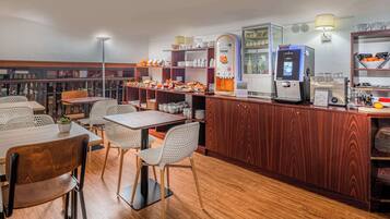 A restaurant with wooden furniture, a coffee machine, and a variety of food items on display.