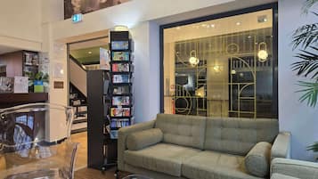 Eine moderne Lobby mit einer Rezeption, einer Couch, einem Glastisch und einem Bücherregal.