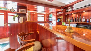 Una zona de bar con mobiliario de madera, un reloj y estanterías con botellas.
