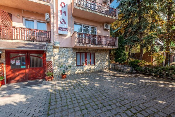 A building with a stone facade, a red door, and a balcony with a metal railing. - Korona Hotel Panzio (Budapest)