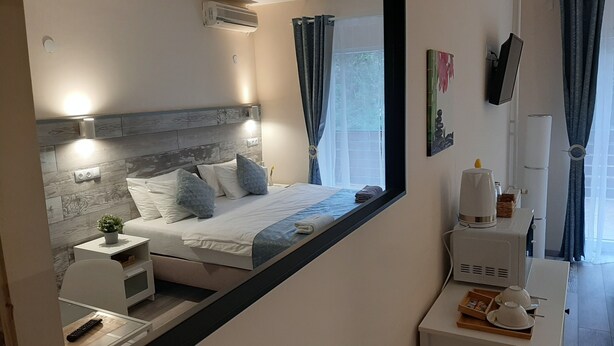 Una habitación de hotel moderna con cama, mesita de noche y un espejo grande.