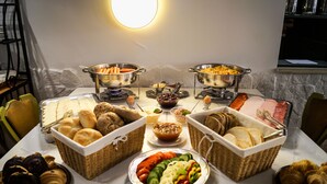 Una mesa de buffet con diferentes opciones de comida, incluyendo pan, pasteles y una ensalada.