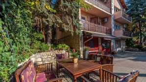 Un área de estar al aire libre con muebles de madera y un fondo de pared de piedra.