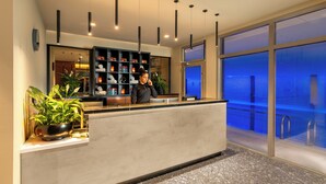 A reception desk with a plant, a shelf with various items, and a view of a pool area. - The Spencer Hotel (Dublin)