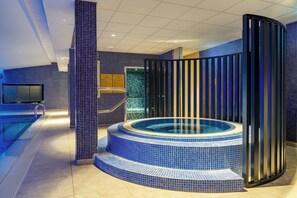 A modern indoor pool area with a hot tub, tiled walls, and a television. - The Spencer Hotel (Dublin)