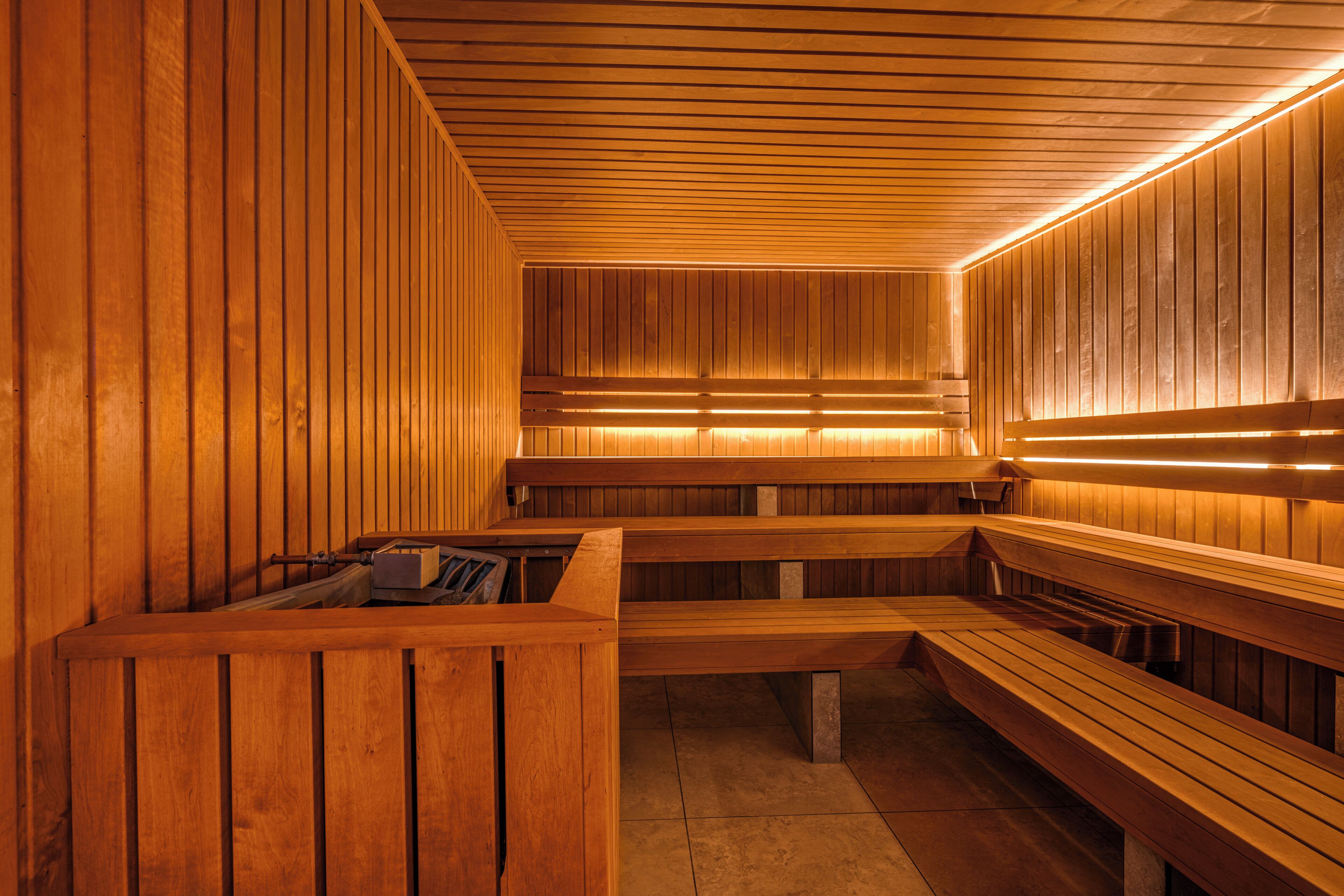 A sauna with wooden benches and a bench with a towel rack.