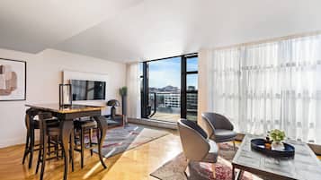 Una sala de estar moderna con comedor, ventanas grandes y vistas a la ciudad.