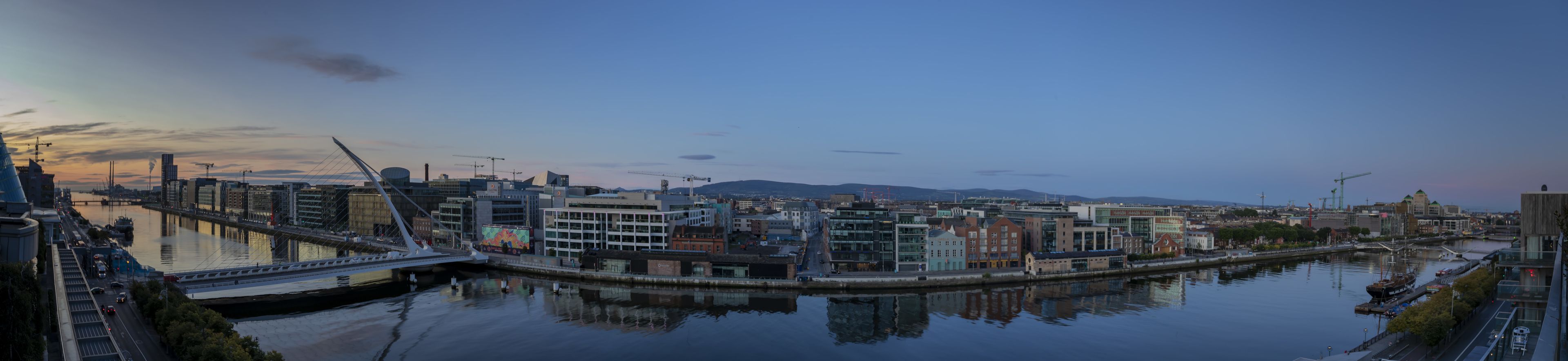 A cityscape with a river, modern buildings, and a bridge.