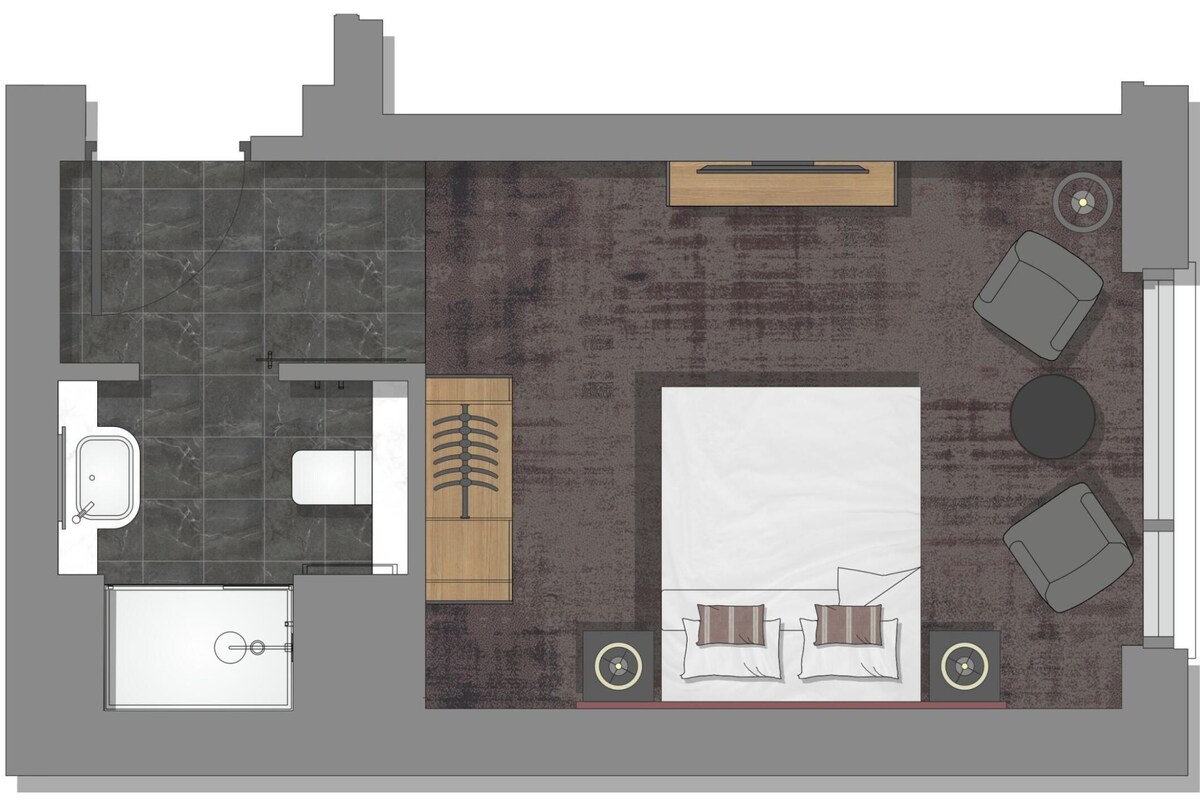 A hotel room layout with a bathroom, a bed, a desk, and a seating area.