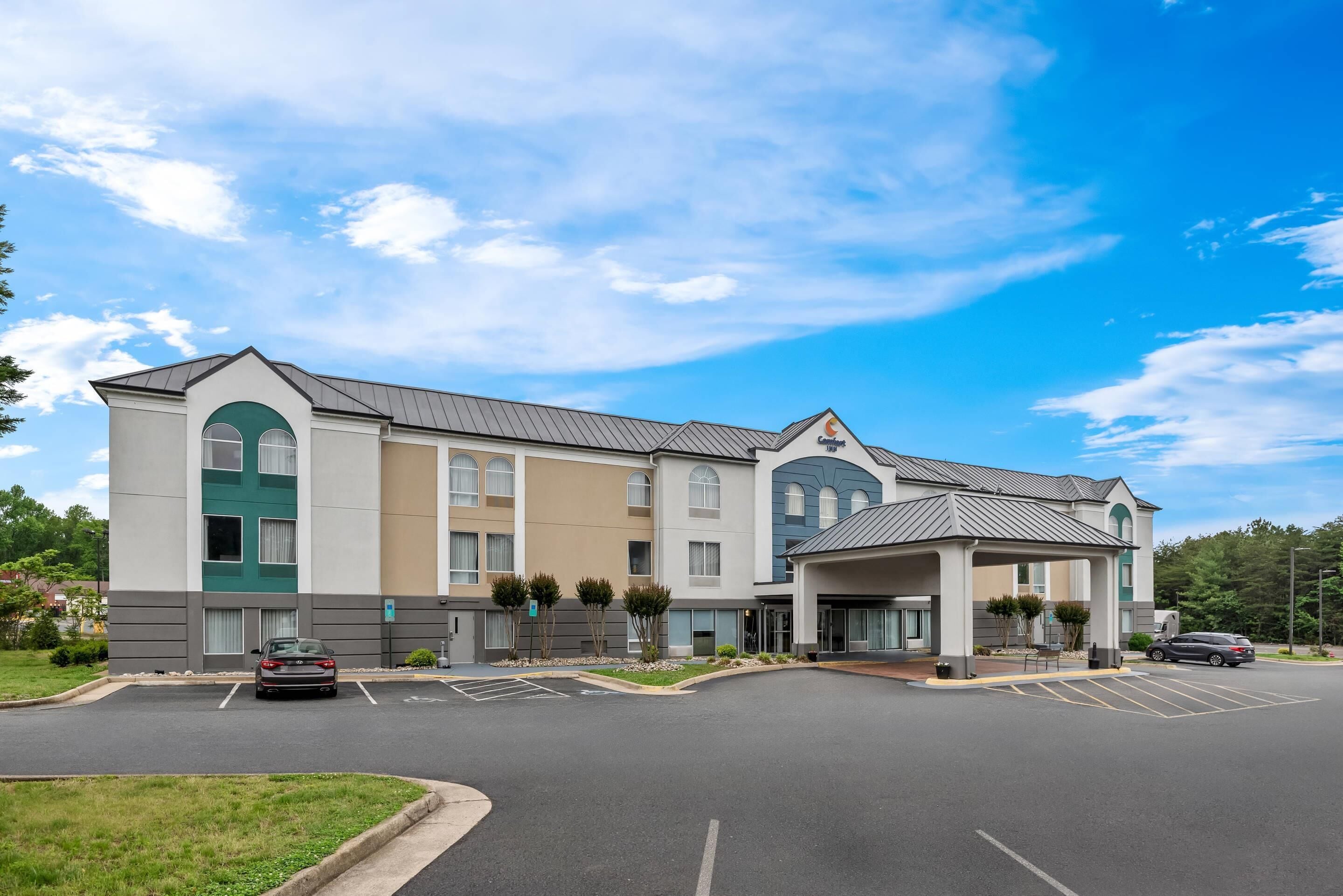 A multi-story hotel with a parking lot and a covered entrance.