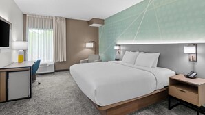 A hotel room with a bed, desk, chair, bedside table, lamp, and a large window with curtains. - Comfort Inn Ruther Glen near Kings Dominion (Ruther Glen)