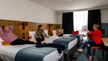 A hotel room with two beds, a desk, and a window with curtains.