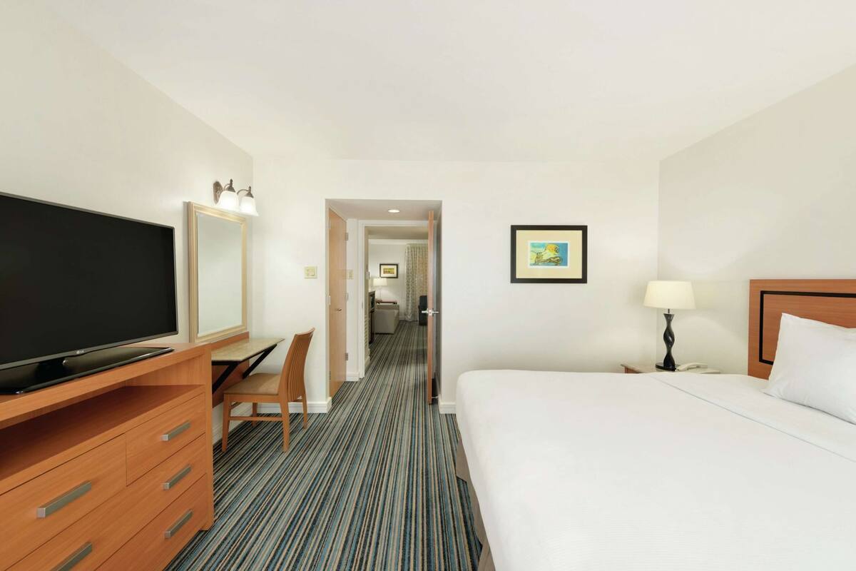 Ein Hotelzimmer mit Bett, Schreibtisch mit Fernseher, Stuhl, Lampe und einem gerahmten Bild an der Wand.
