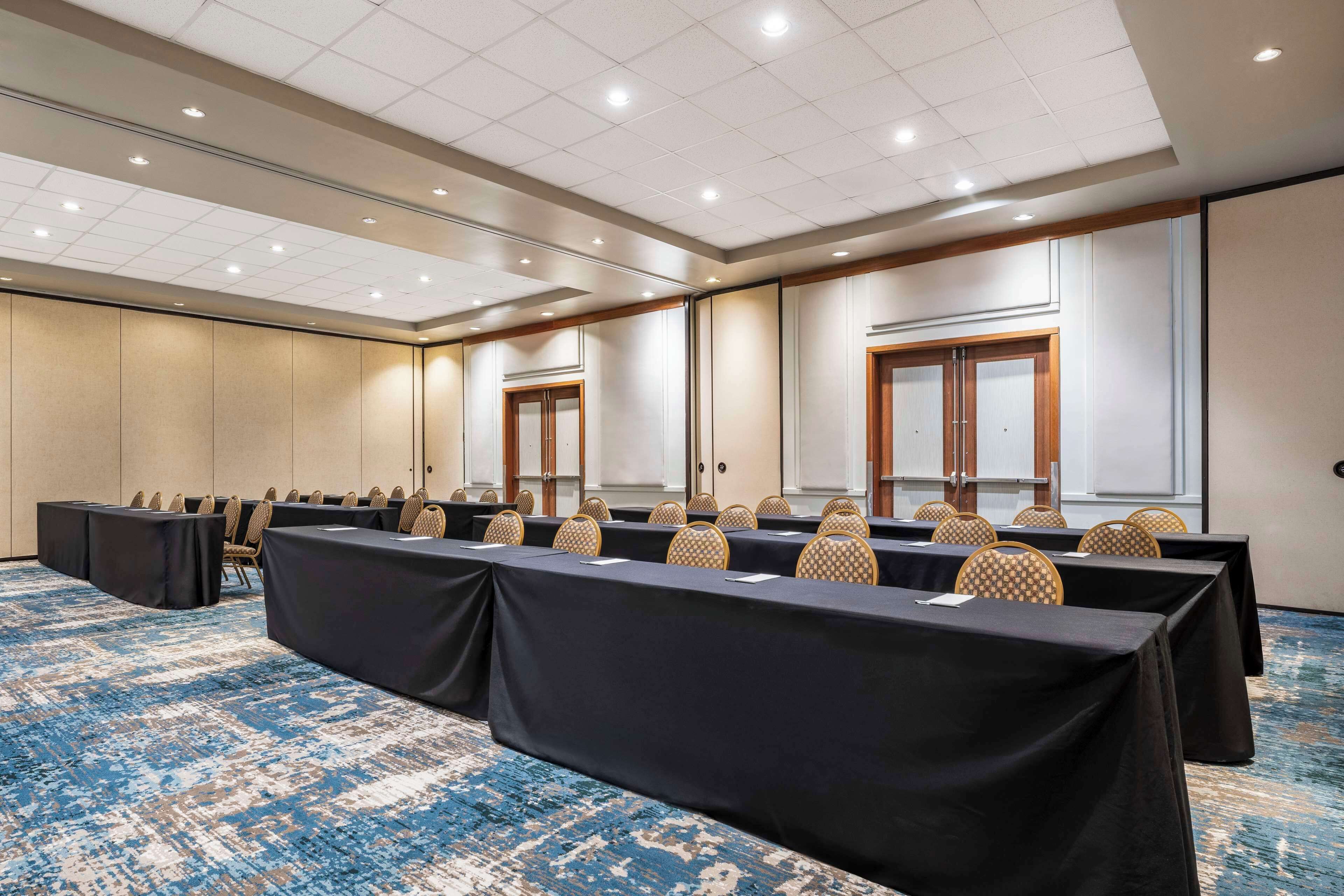 A conference room with a long table, chairs, and a carpeted floor.