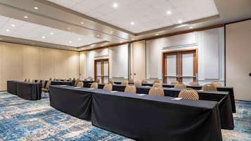 A conference room with a long table, chairs, and a carpeted floor.