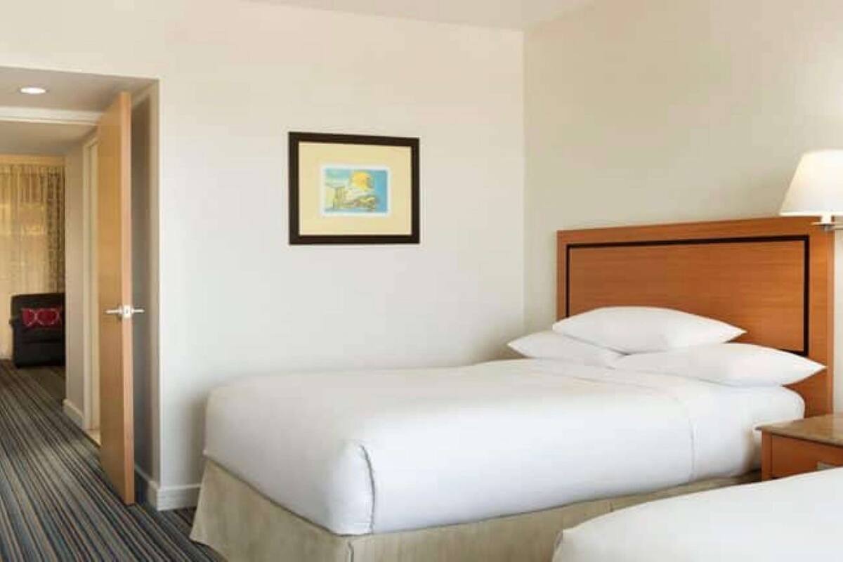 Ein Hotelzimmer mit einem großen Bett, einem Nachttisch, einem Sessel und einer Tür zu einem anderen Raum.