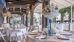 Un salón de banquetes con mesas redondas dispuestas para un evento formal, con manteles blancos, vajilla ordenada y centros de mesa florales.