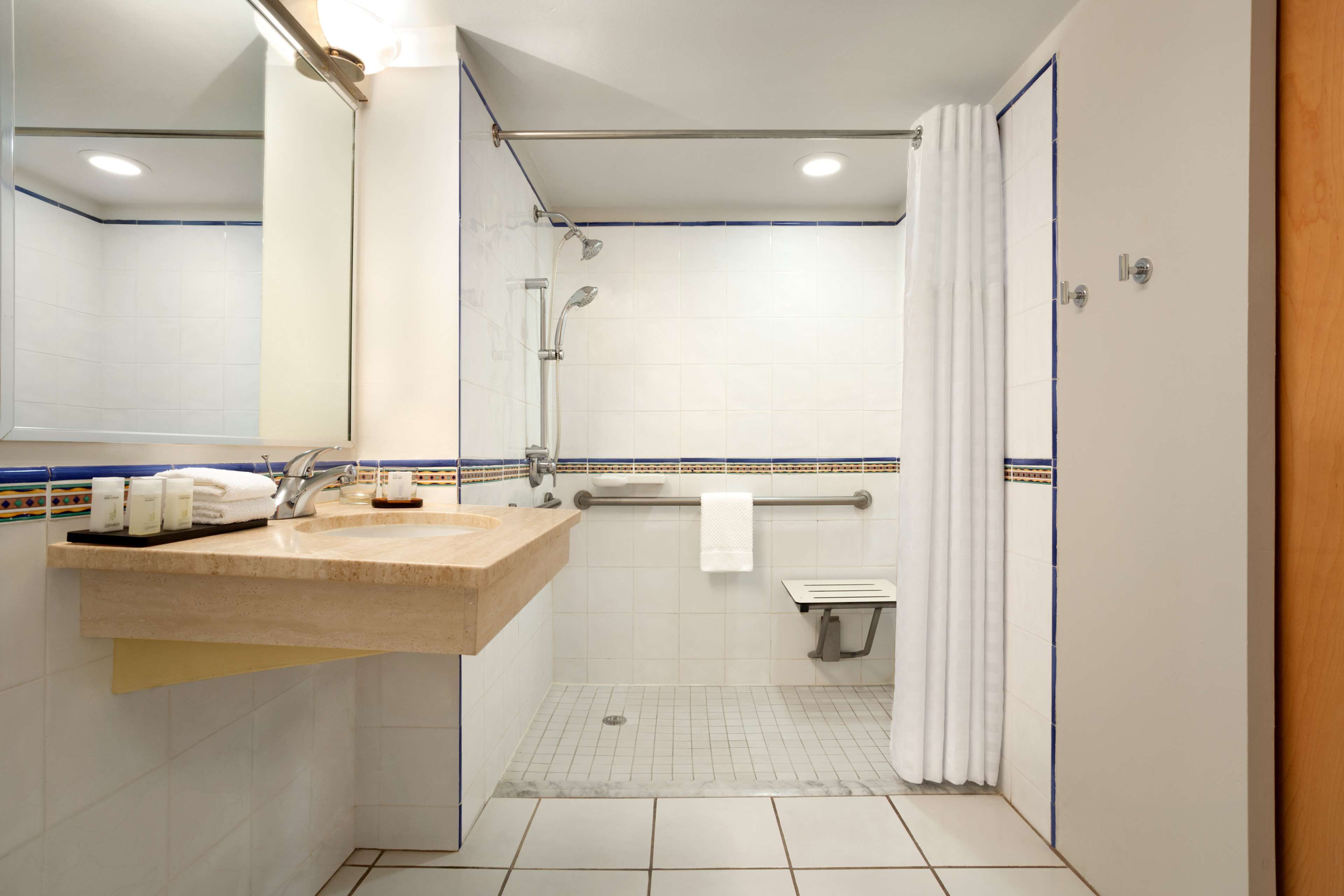 Un baño moderno con lavabo, espejo, ducha e inodoro.