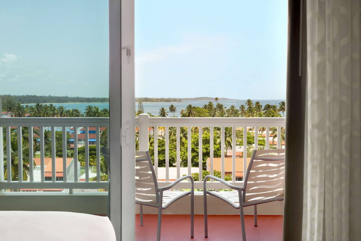 Ein Balkon mit Blick auf das Meer und Palmen.