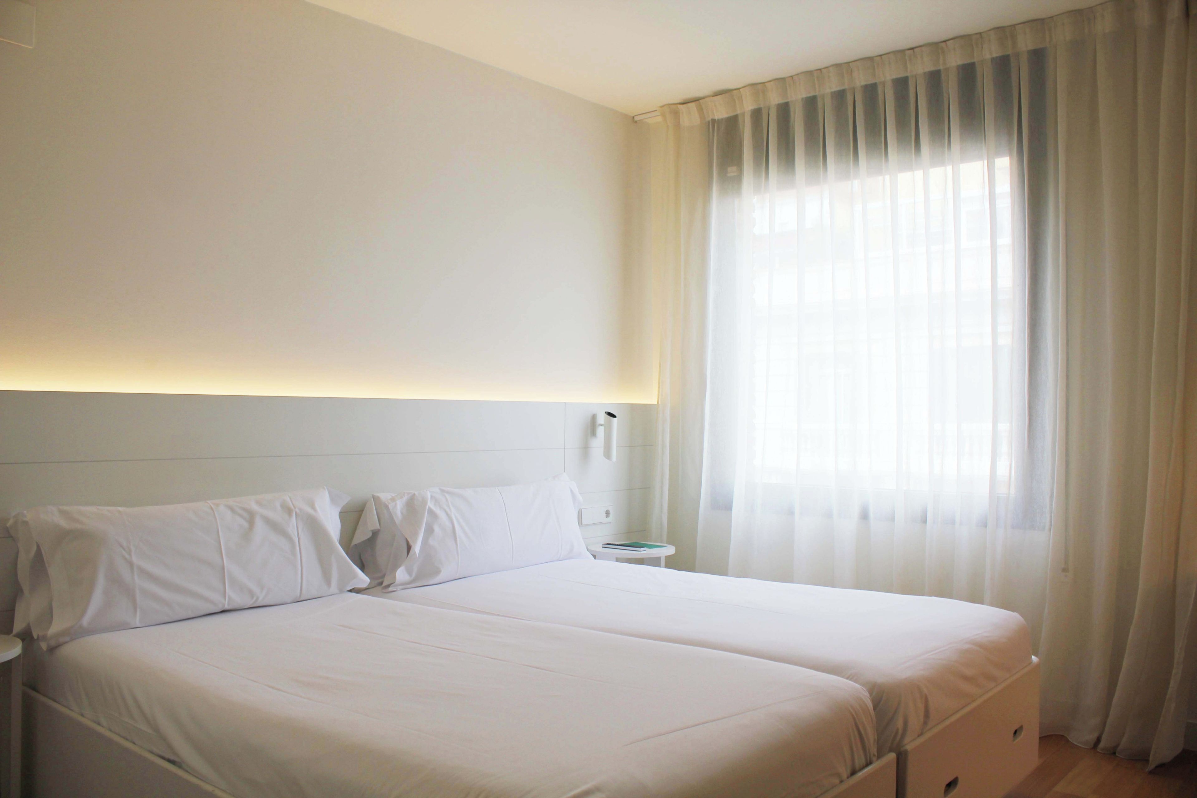 Cama doble con sábanas blancas en una habitación de hotel.