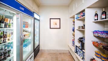 A narrow corridor with a refrigerated beverage display on the left and shelves stocked with snacks and beverages on the right.