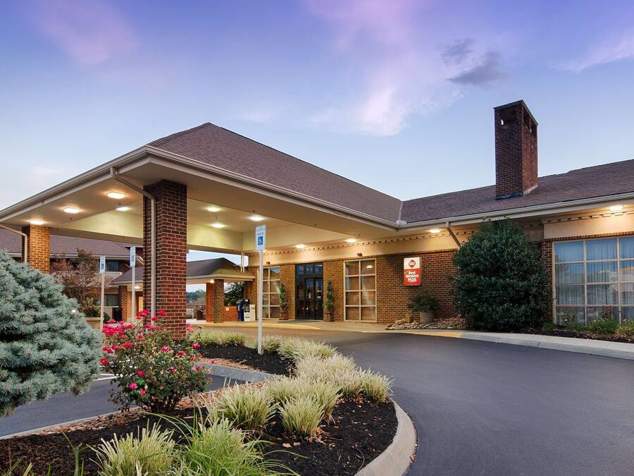A hotel with a brick facade, a covered entrance, and a large window on the right.