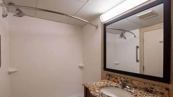 A bathroom with a shower, a sink, and a mirror.