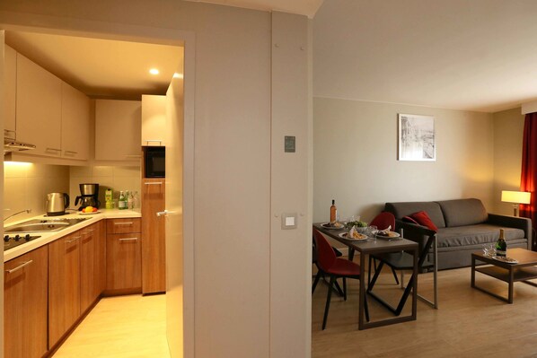 Una cocina moderna con armarios de madera y un comedor con sofá gris y sillas rojas.