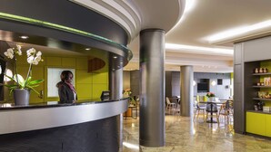 Un espace d’accueil moderne avec un comptoir incurvé, une réceptionniste et une orchidée en pot.